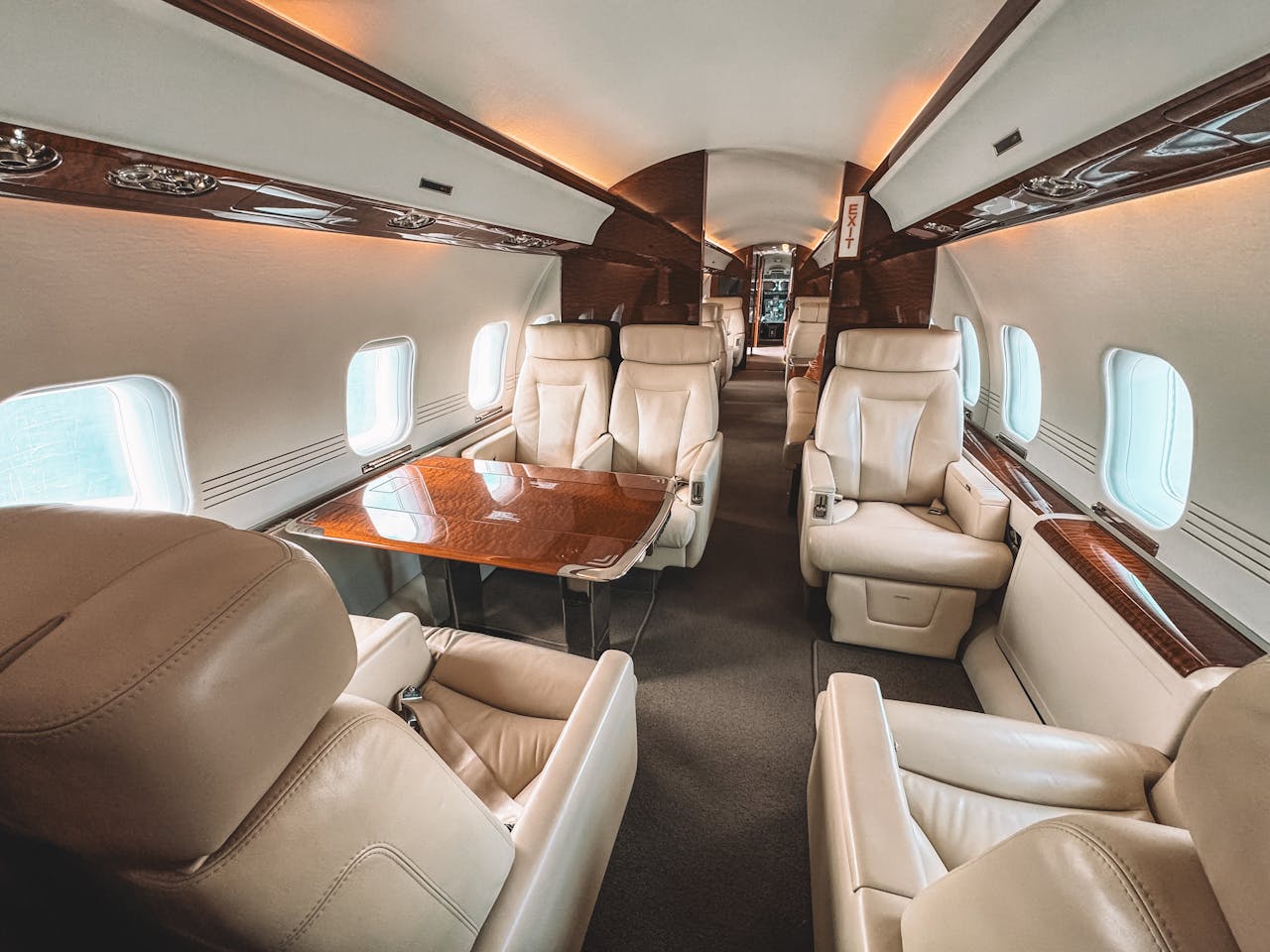 about-01 Luxurious interior of a private jet showcasing leather seating and elegant wooden trim.