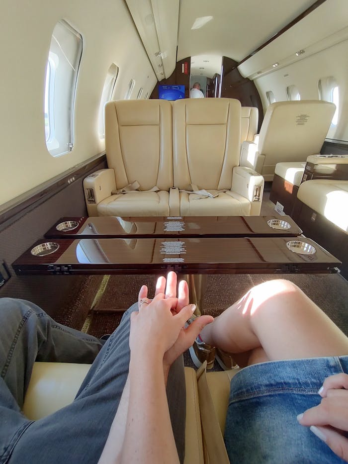 gallery-1 Couple holding hands inside a luxurious private jet with elegant leather seating.