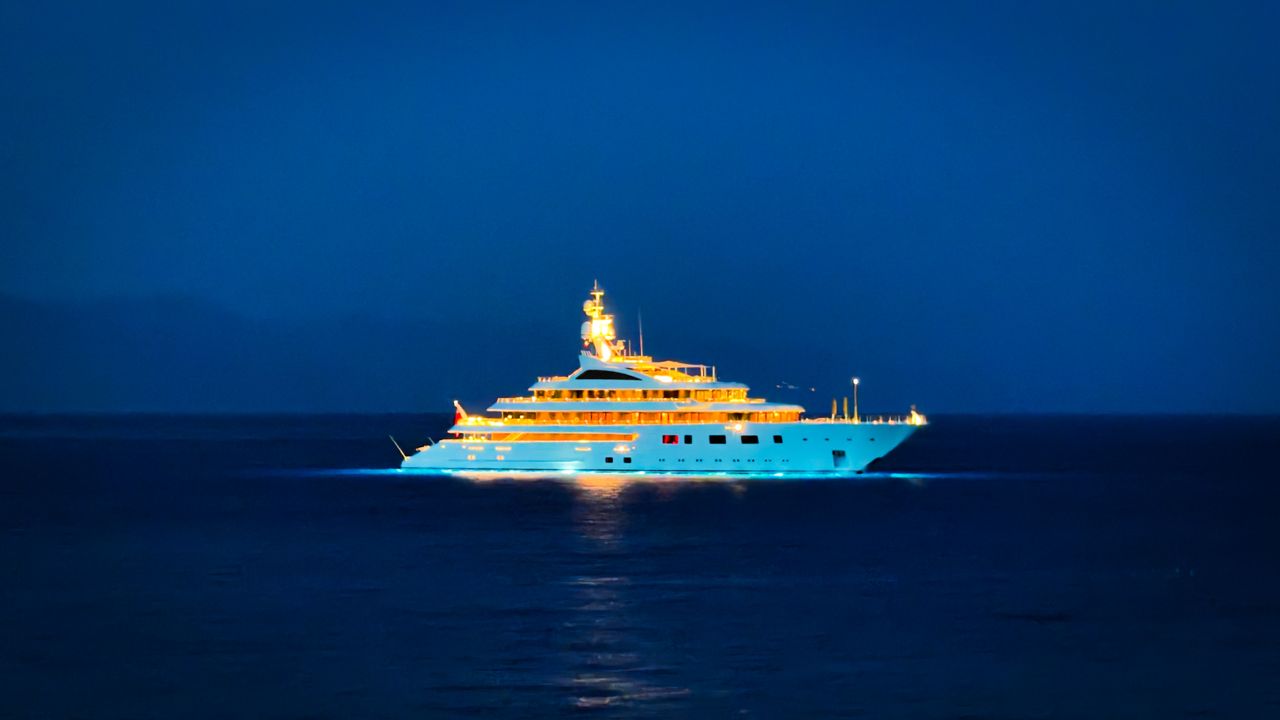 gallery-2 A luxury yacht illuminated beautifully against the dark ocean night, exuding opulence.