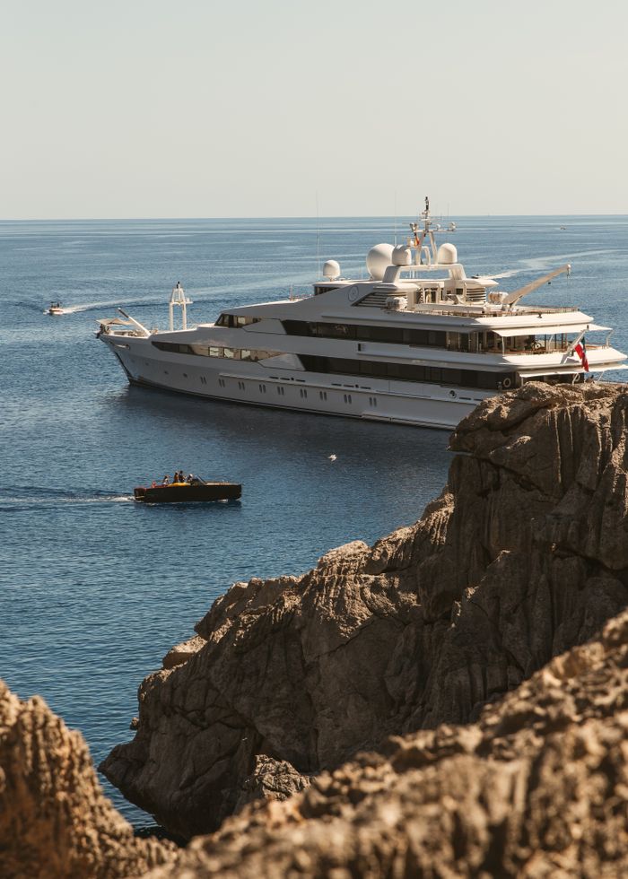 gallery-3 A luxury yacht cruising near rocky cliffs on a sunny day in Spain, showcasing adventure and travel.